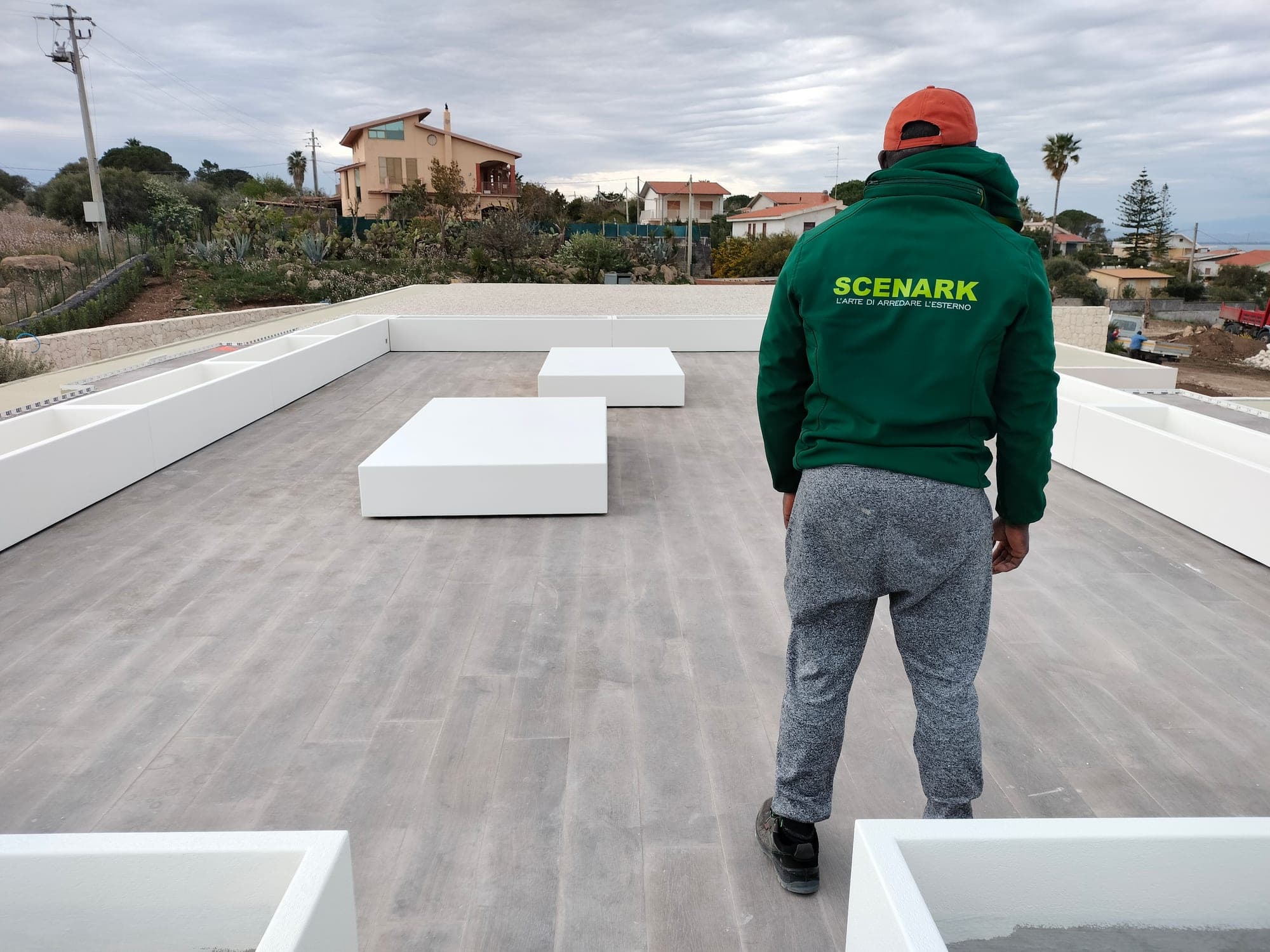 Un posatore Scenark su un grande terrazzo, tra fioriere bianche lungo il bordo e sedute squadrate appena posate