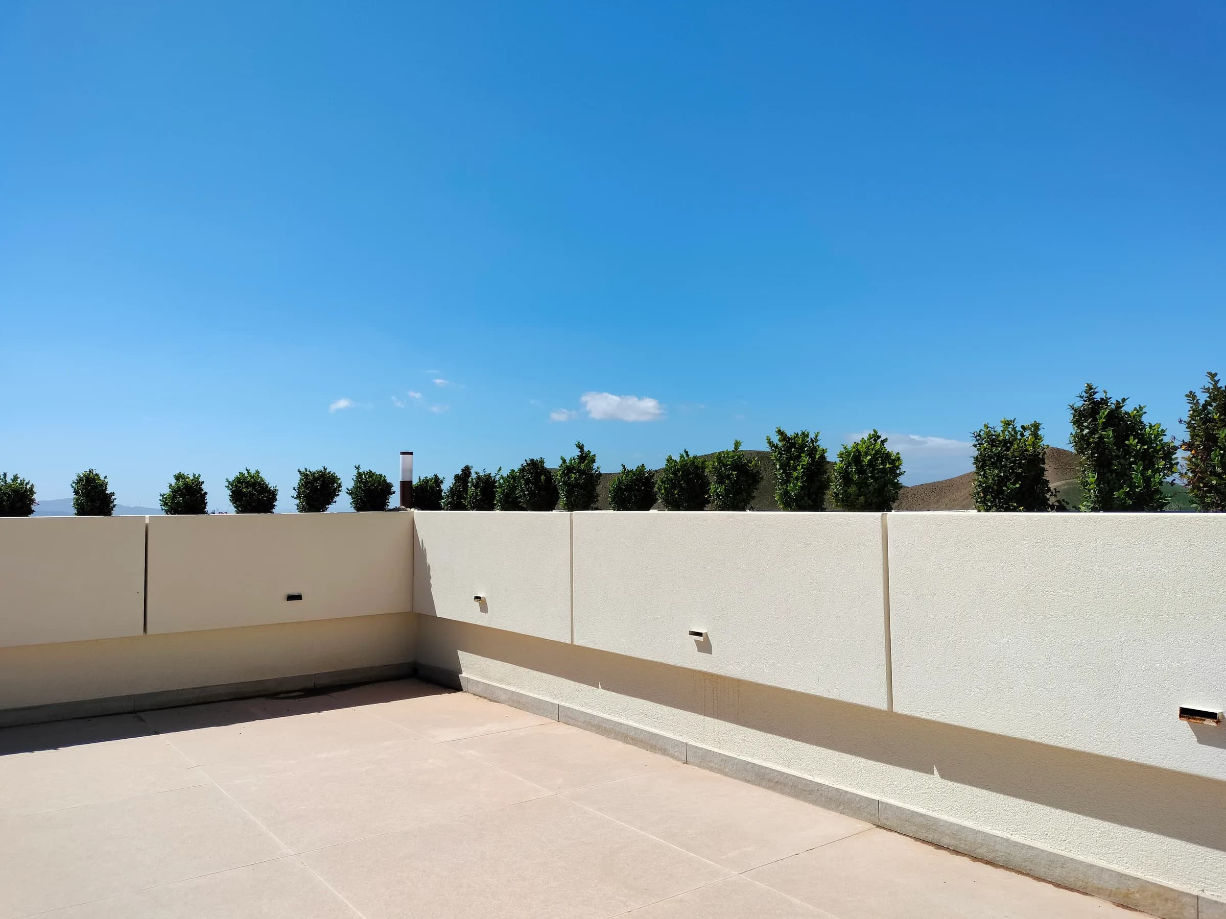 Angolo di terrazza con fioriere parapetto e piccoli alberi