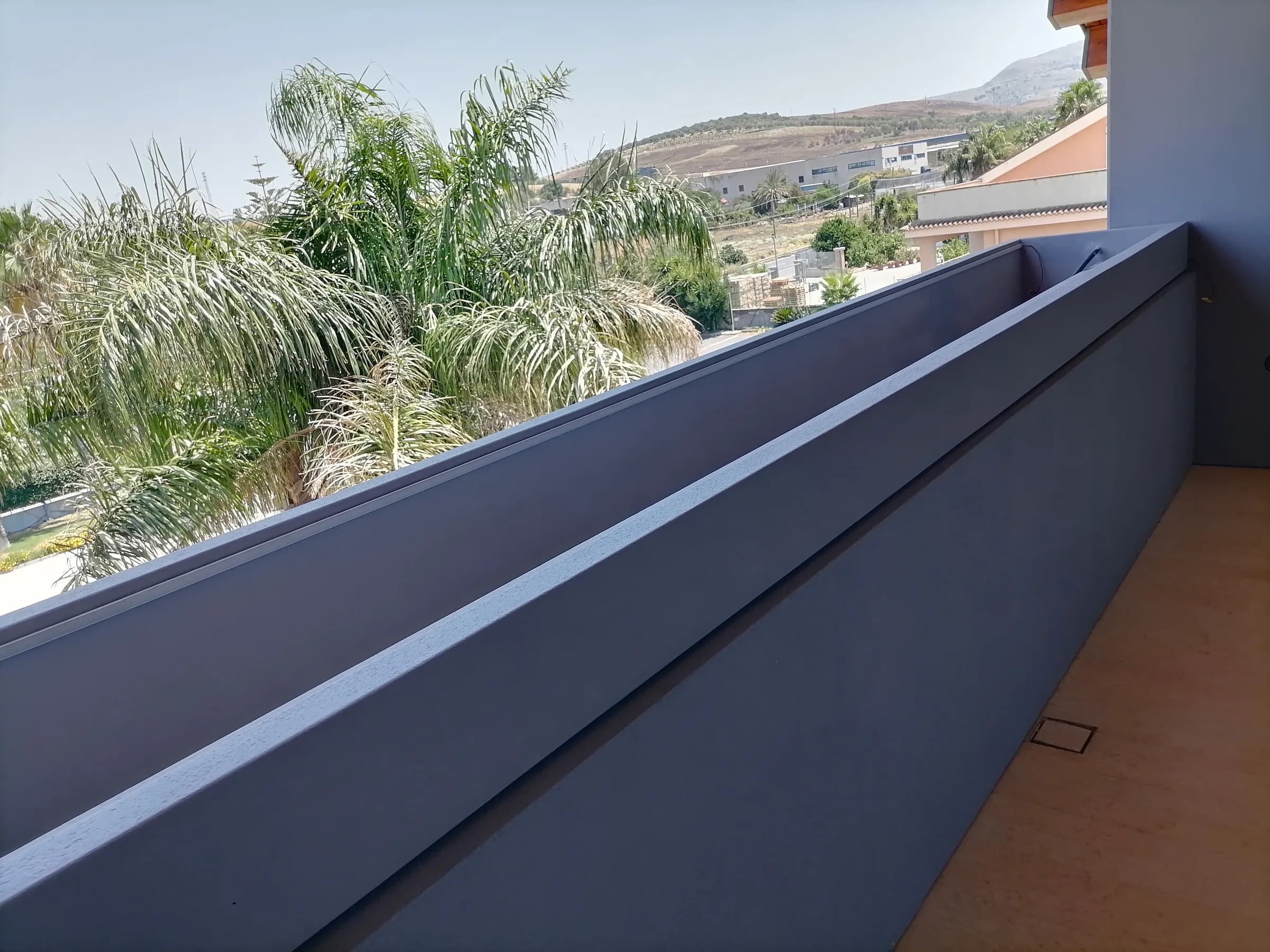 Fioriera parapetto grigio scuro su un balcone tra le palme