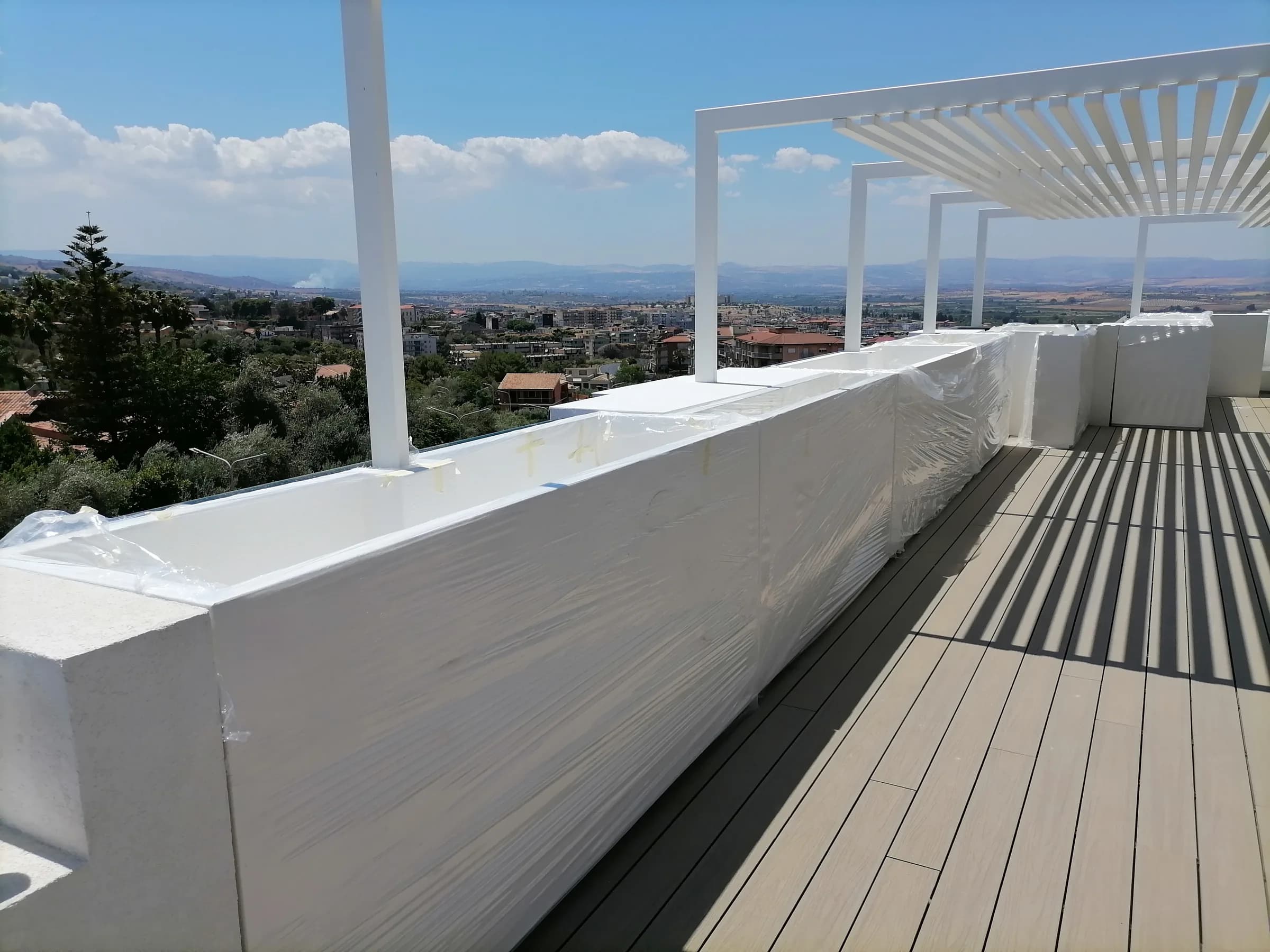 Fioriere parapetto ancora imballate su una terrazza con pergola