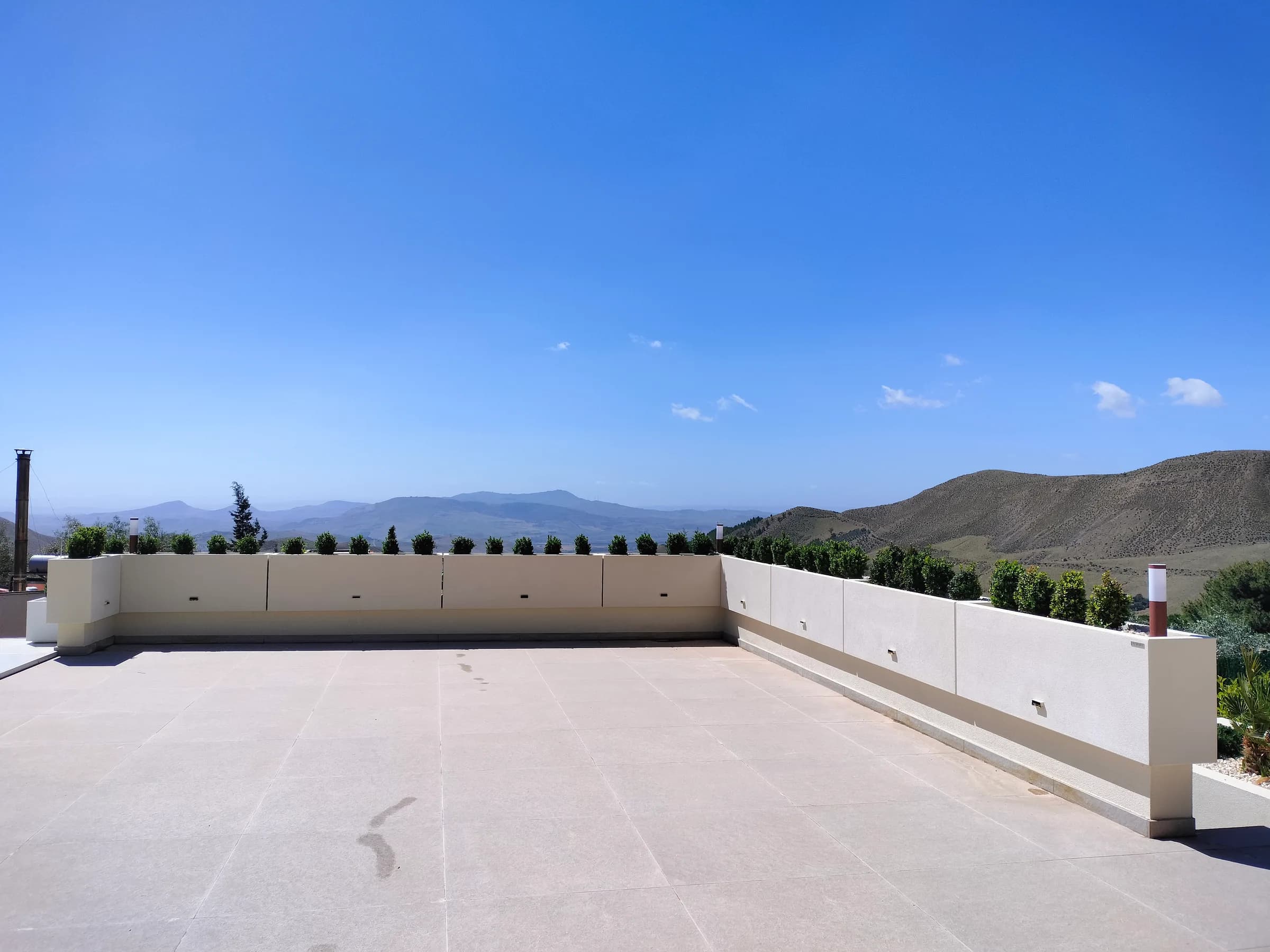 Terrazza panoramica con fioriere parapetto e siepe verso le colline